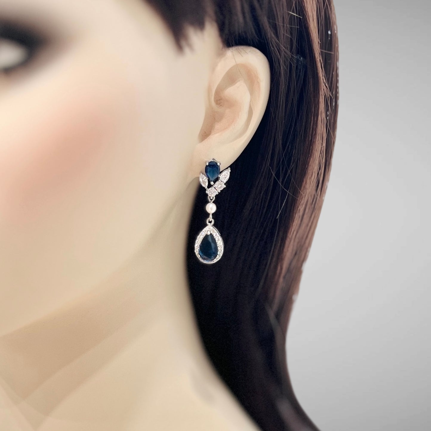 Close-up of a woman wearing a decorative earring with blue gemstones.