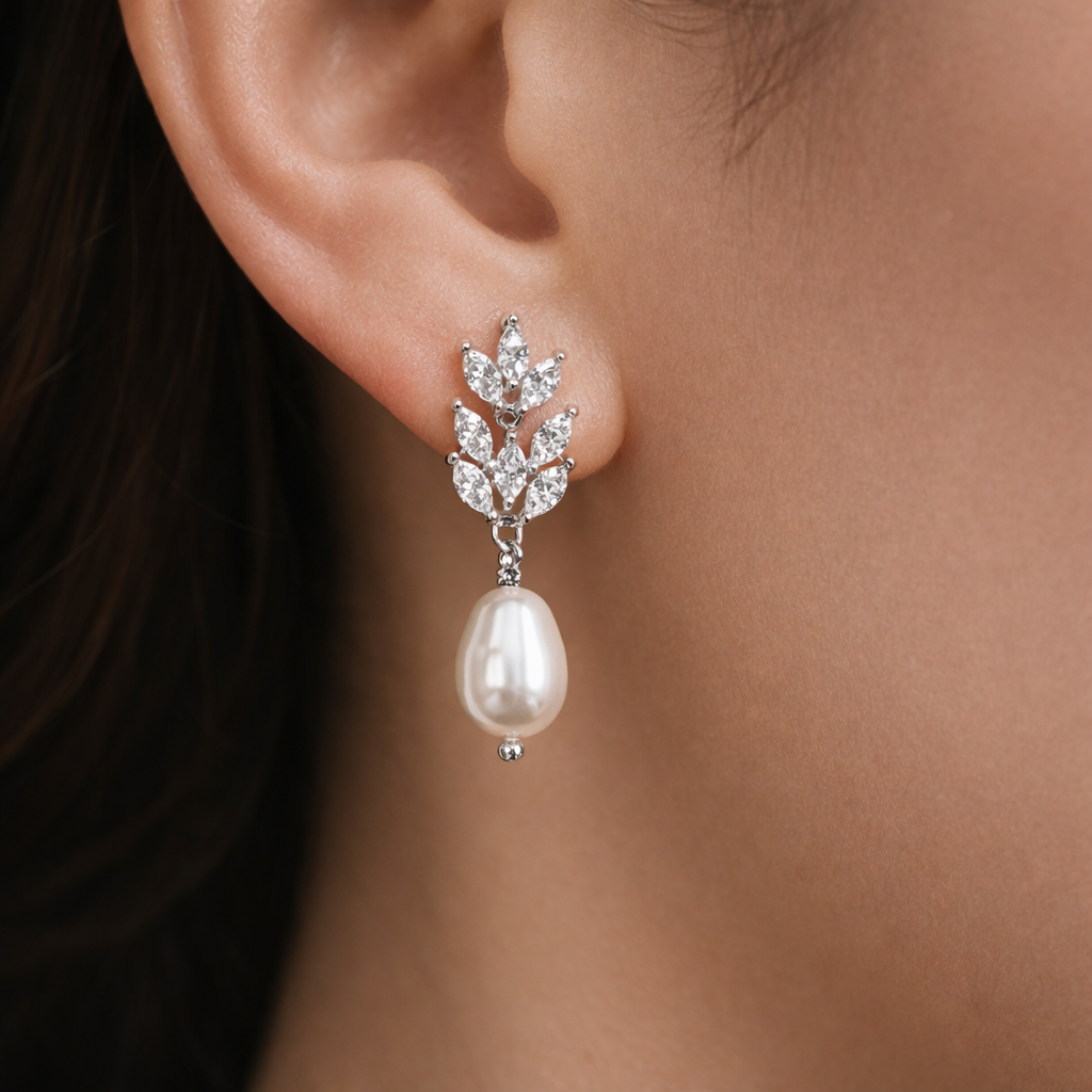 Close-up of a pearl earring with leaf-like design on an ear.