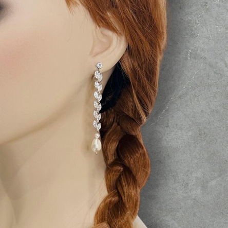 Pearl earring worn by a mannequin with braided hair against a gray background