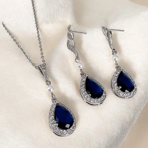 Jewelry set with blue teardrop stones on a white background