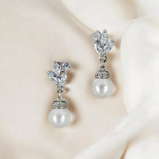 Pearl and crystal drop earrings on a soft beige background