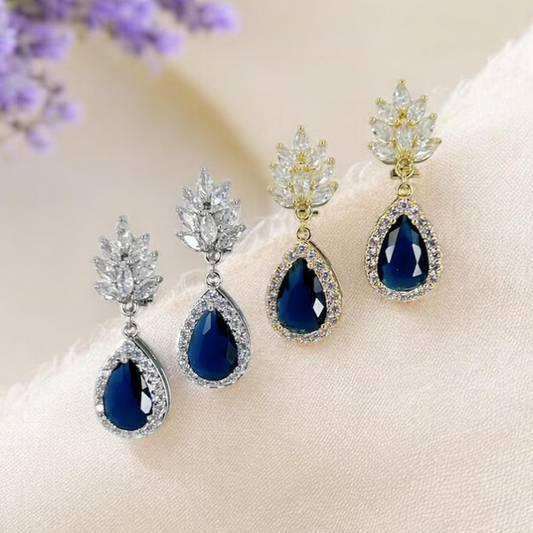 2 Pair of sapphire blue teardrop clip on earrings with intricate designs on a soft background