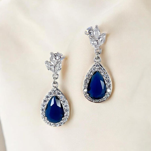 Pair of blue teardrop earrings with silver accents on a light background
