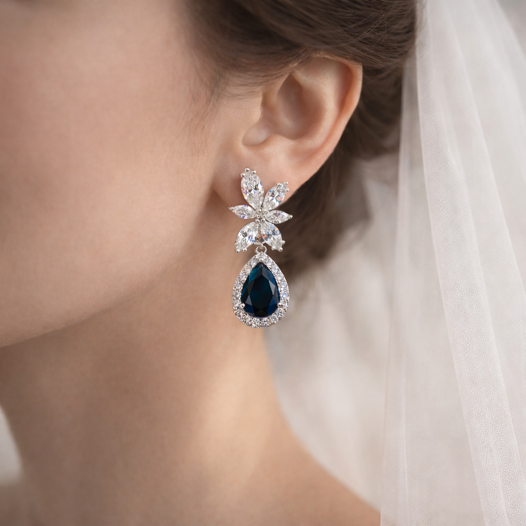 Close-up of a woman wearing a pair of earrings with a blue gemstone.