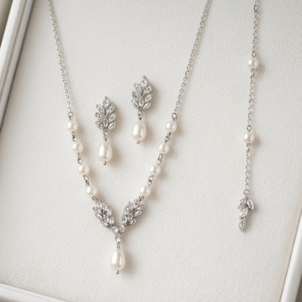 Pearl necklace and earrings set on a light gray background