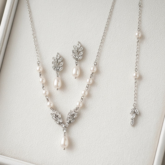 Pearl necklace and earrings set on a light gray background