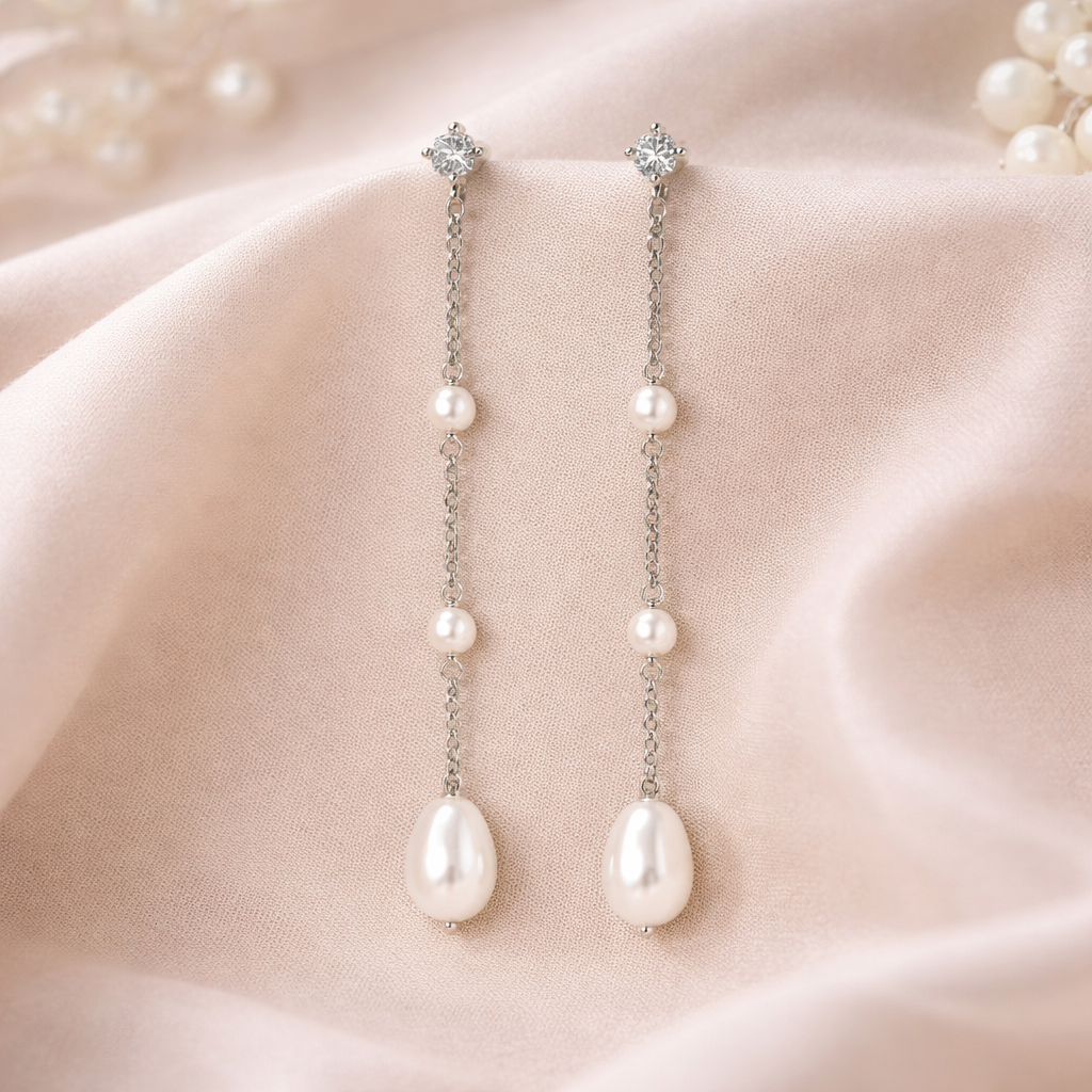 Pearl drop clip on earrings on a soft pink fabric background