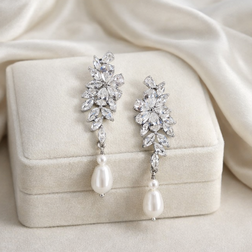Pair of silver earrings with pearls on a beige jewelry box