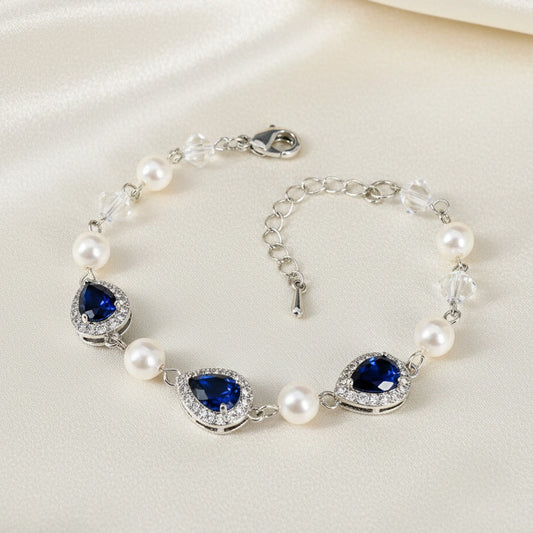 Silver bracelet with blue gemstones and pearls on a white background