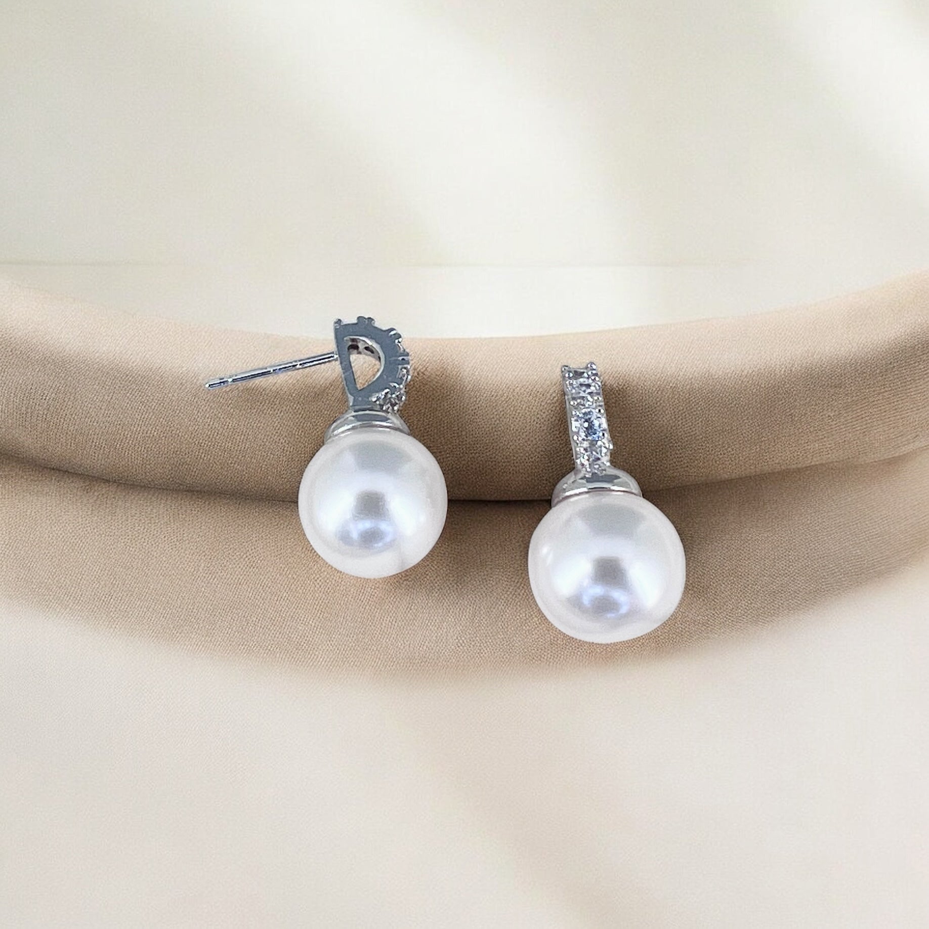Handmade pearl wedding earrings showing luminous round pearls and silver crystal-set posts