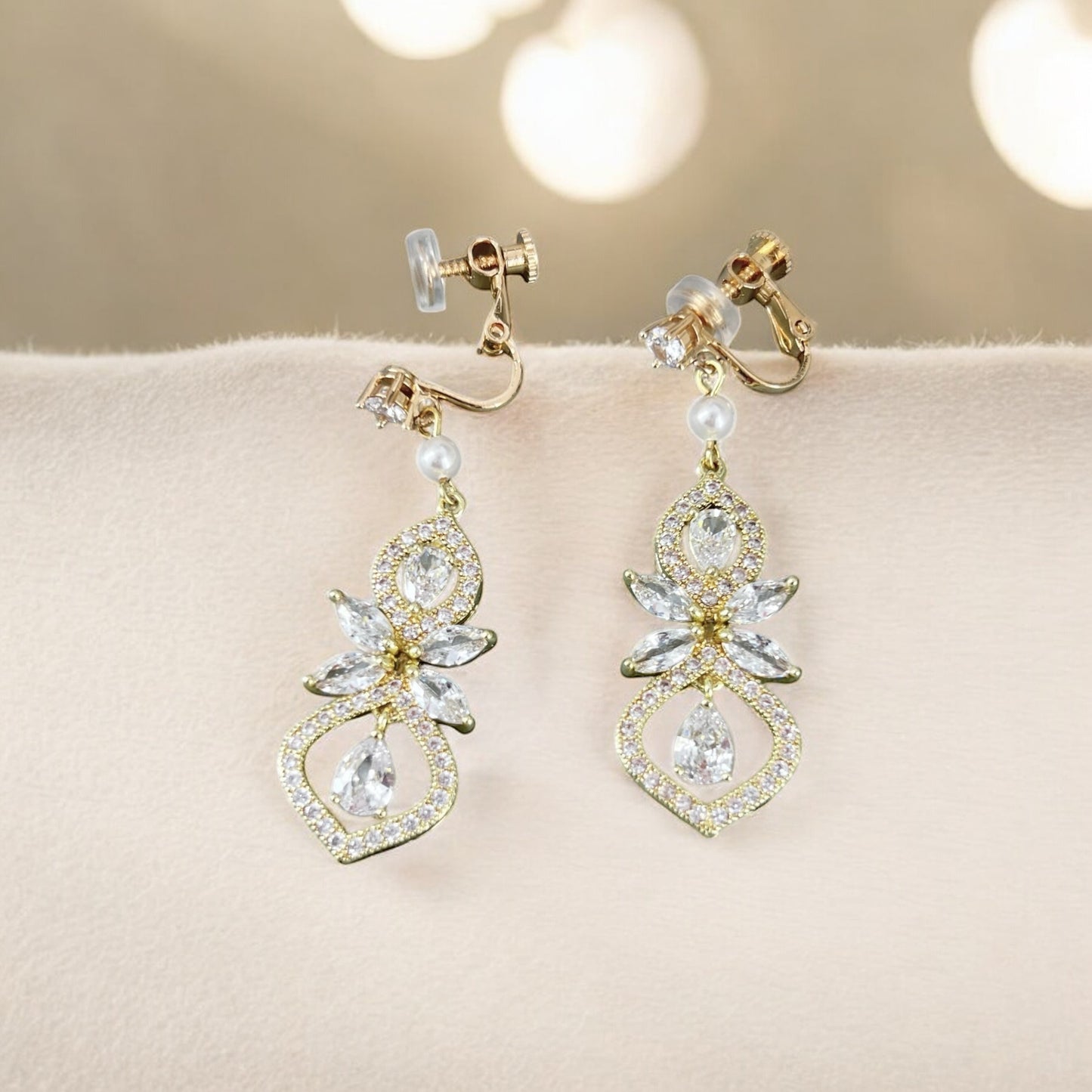 Pair of gold and crystal earrings on a soft surface with a blurred background
