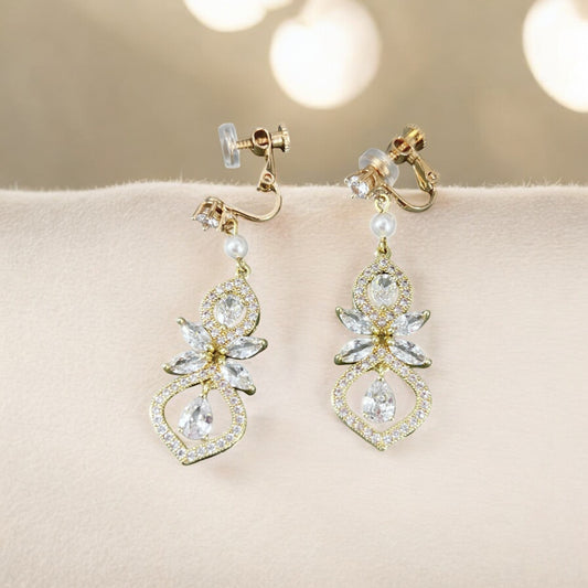 Pair of gold and crystal earrings on a soft surface with a blurred background