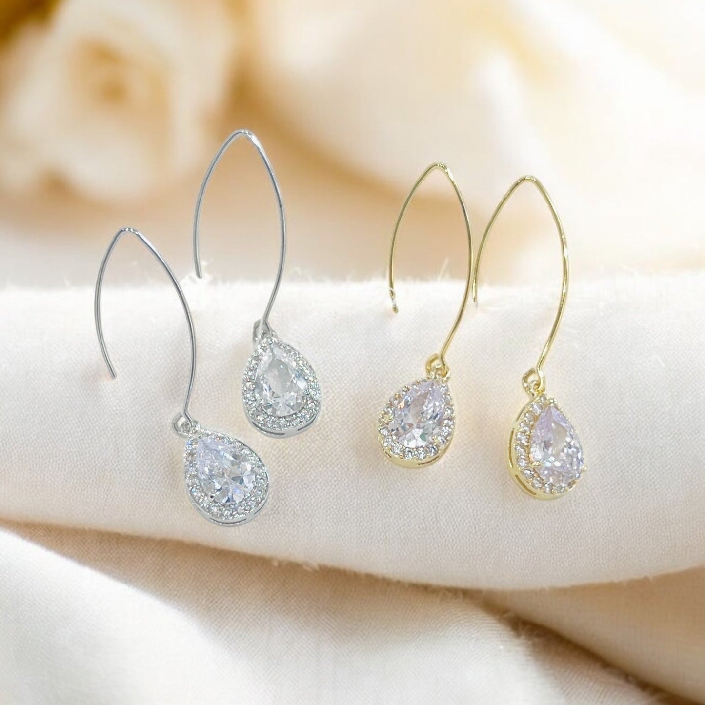 Clear teardrop crystal drop earrings with silver hooks on soft background