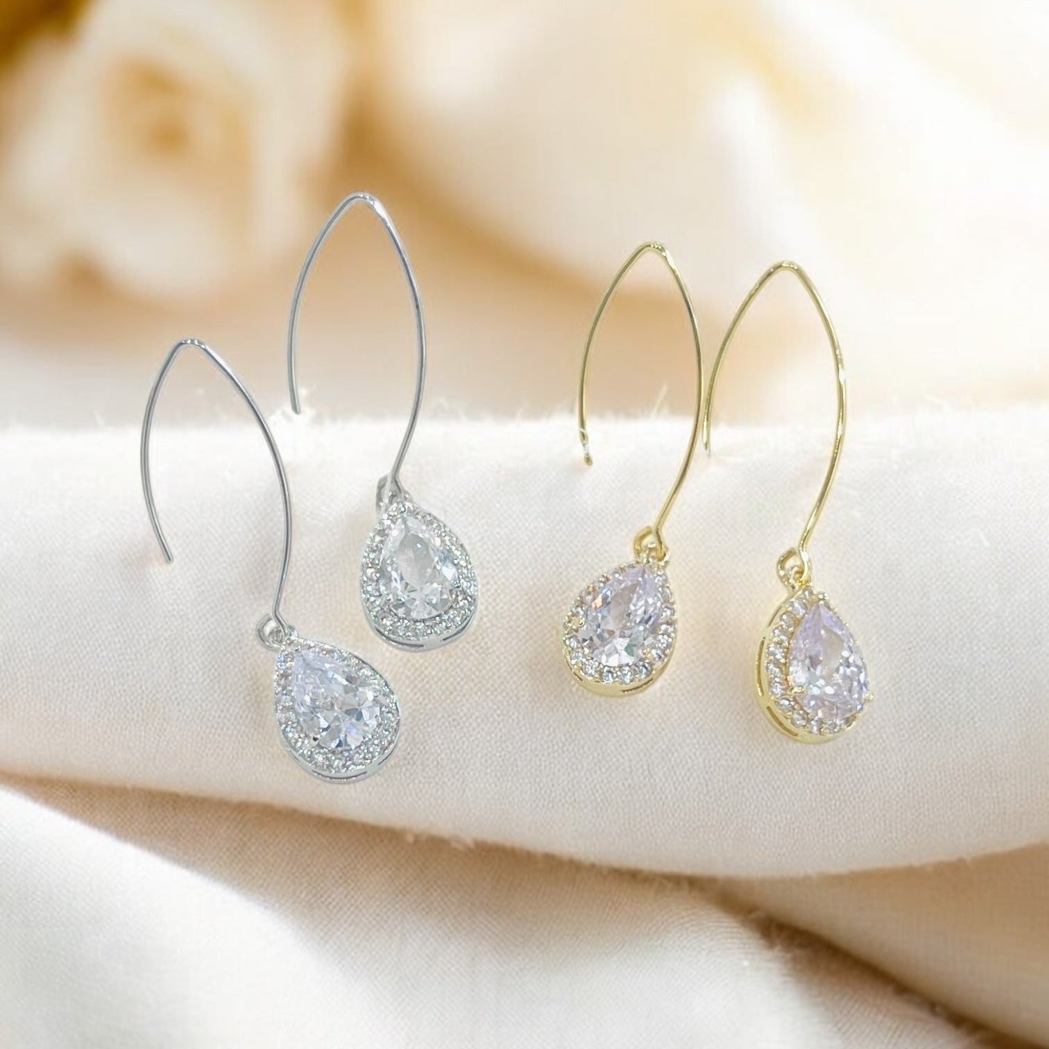 Clear teardrop crystal drop earrings with silver hooks on soft background