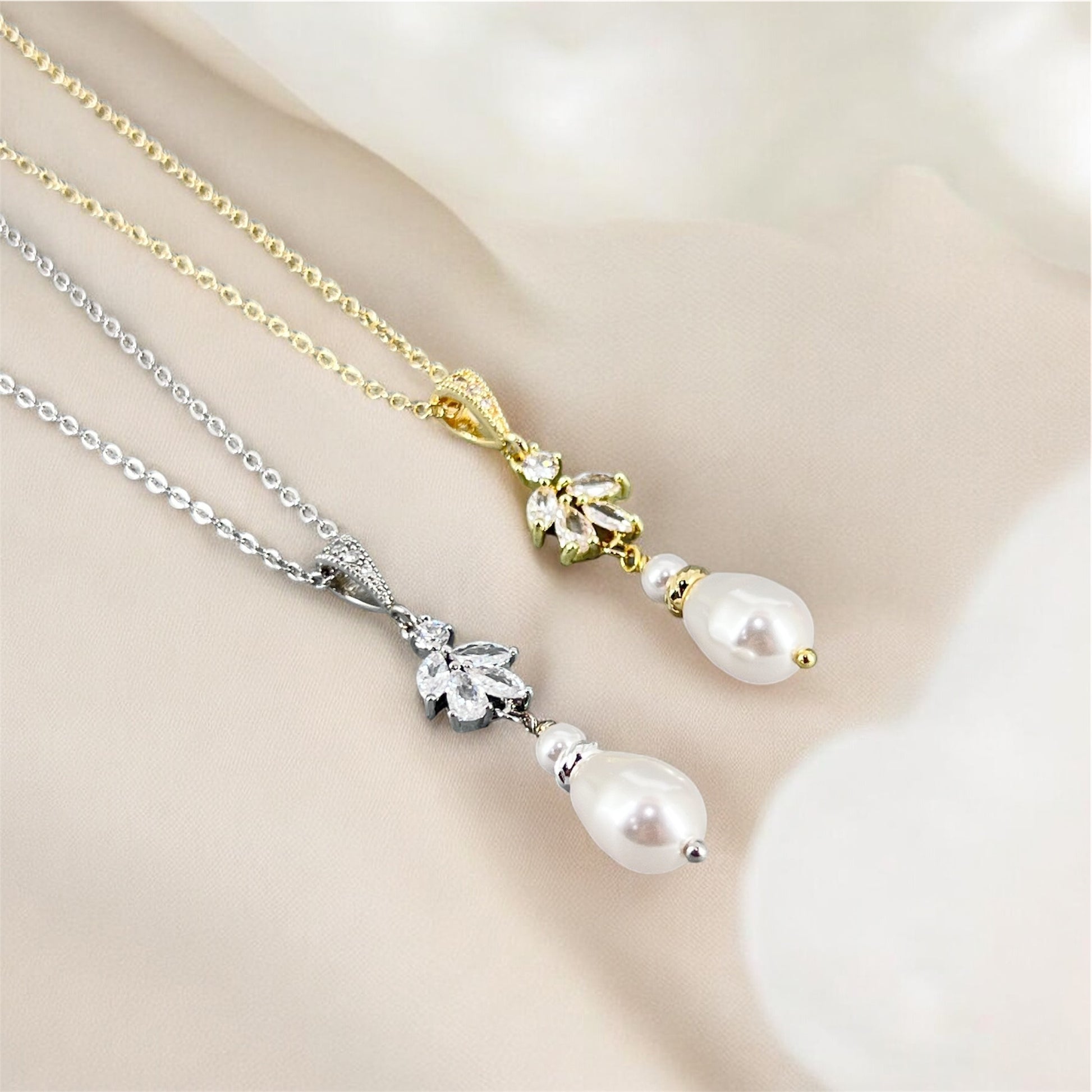 CZ floral marquise and pearl necklaces in gold and silver settings on a soft beige background
