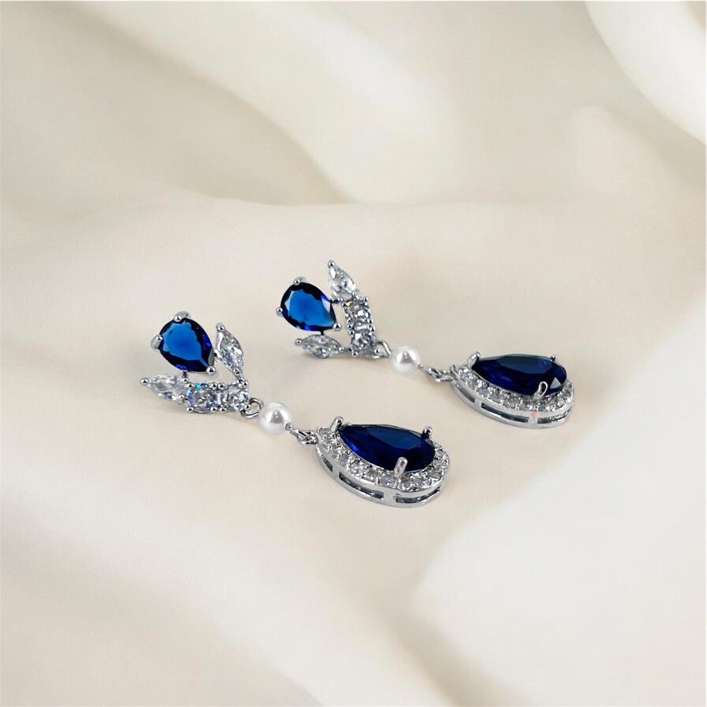 Pair of blue teardrop earrings on a beige background