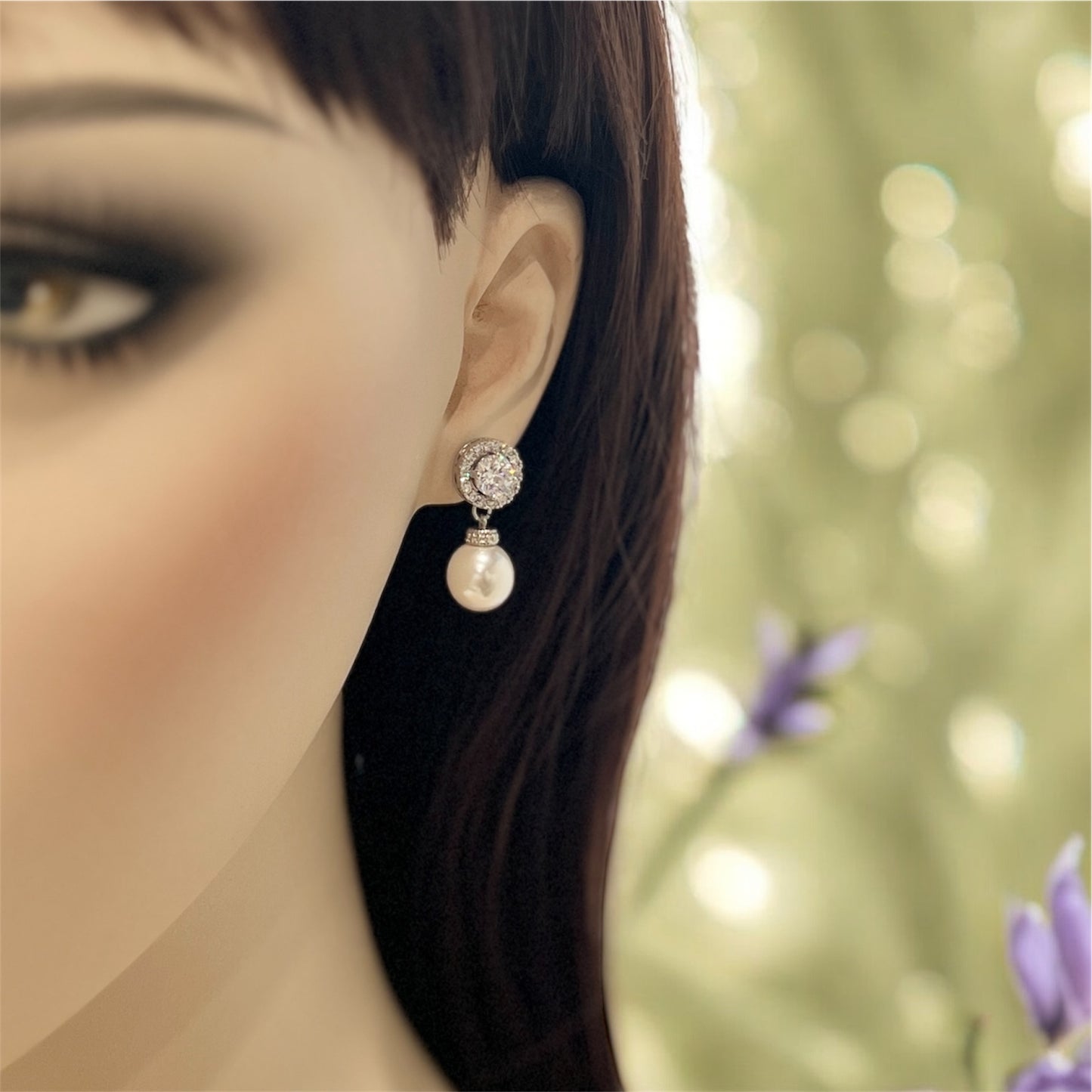 Close-up of a woman's ear wearing a pearl earring with a blurred natural background