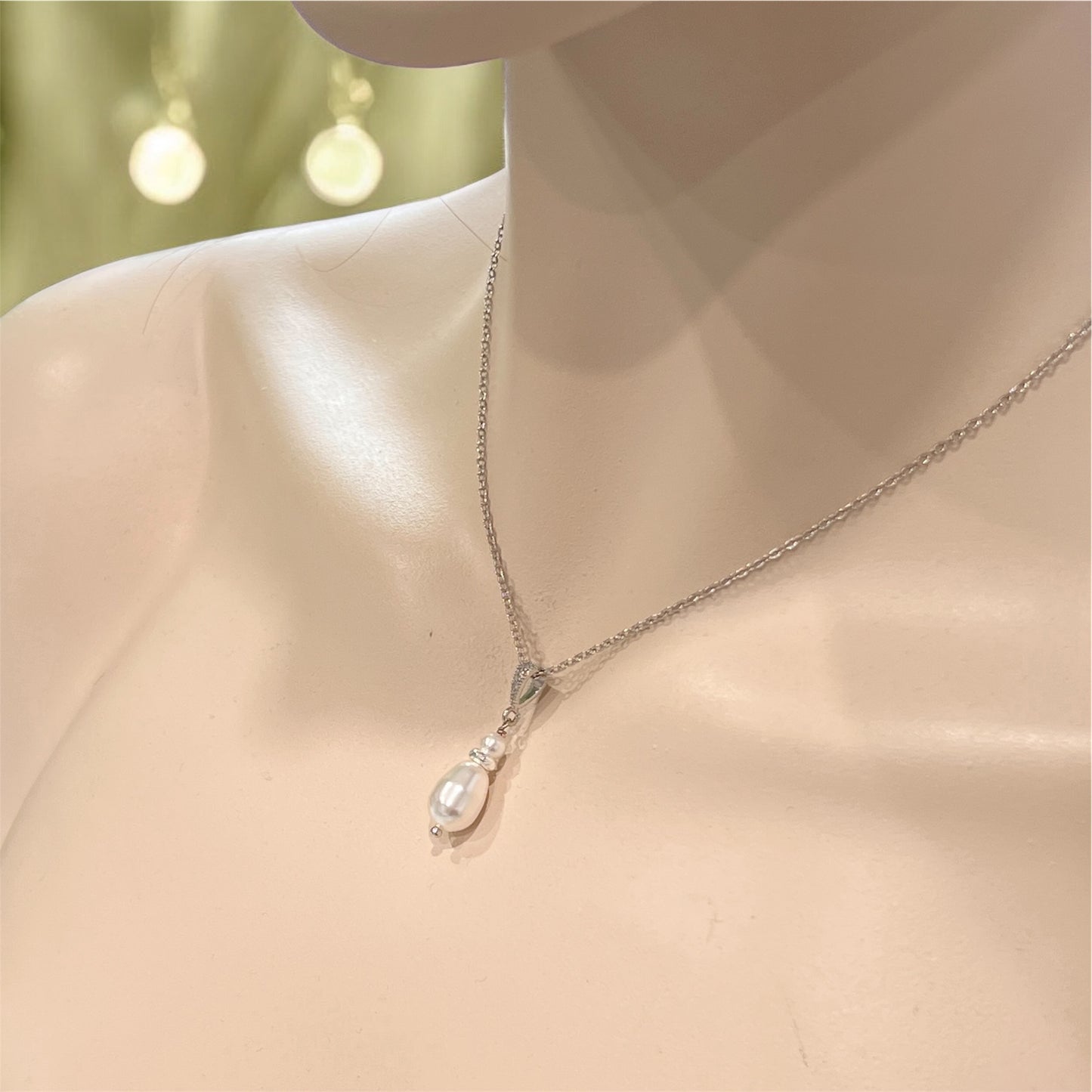 Pearl pendant necklace on a mannequin neck against a blurred background