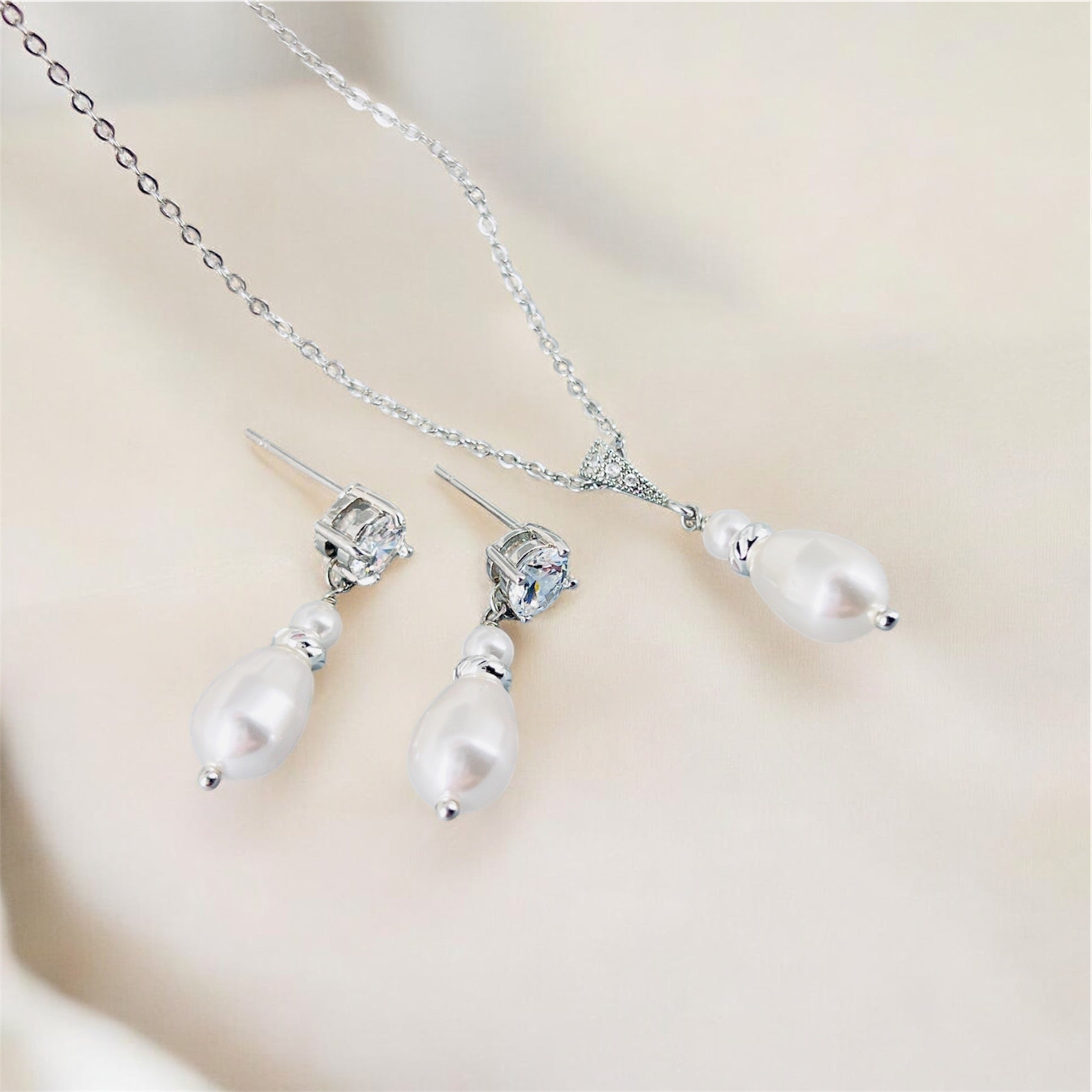 Pearl necklace and earrings set on a light background