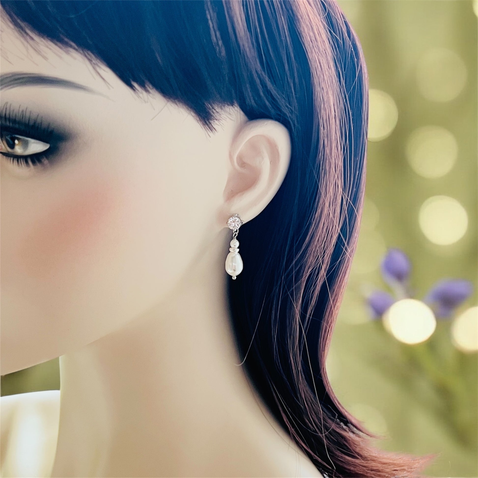 Close-up of a woman wearing a pear-shaped pearl earring with a blurred background