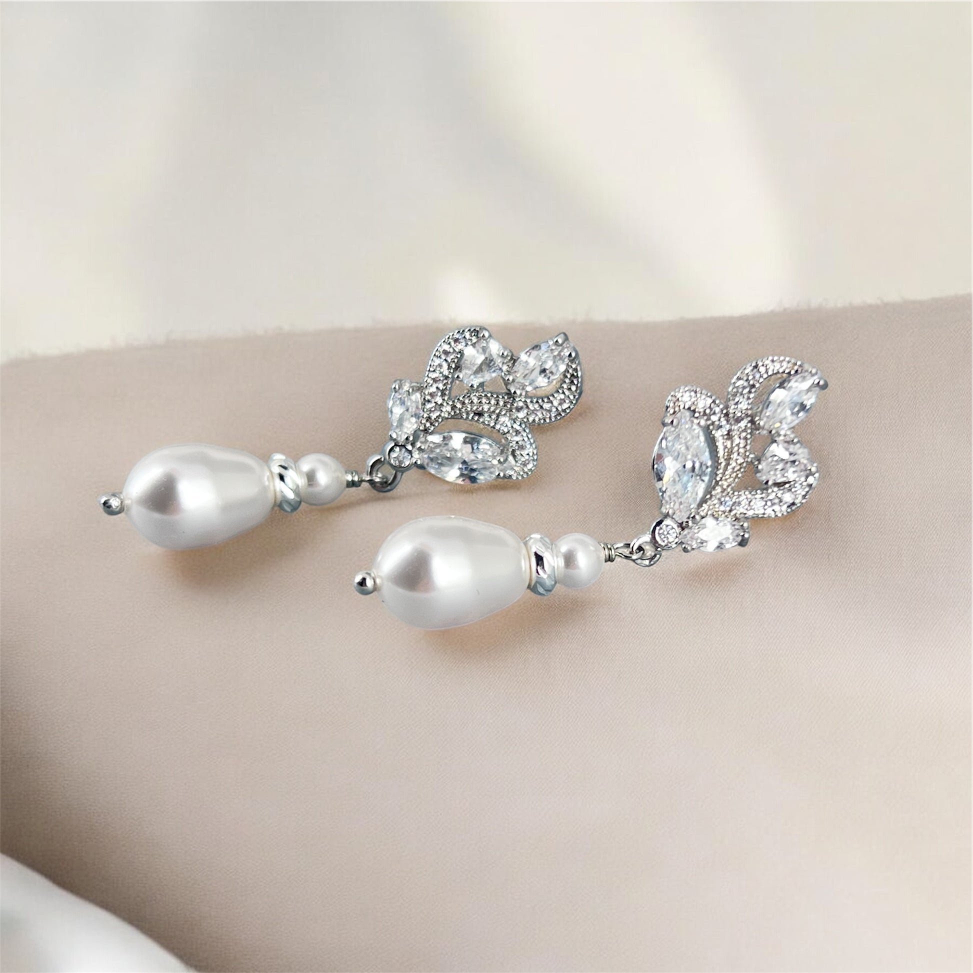 Pearl and marquise earrings on a neutral background