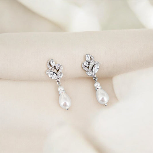Pair of pearl and crystal earrings on a soft beige background