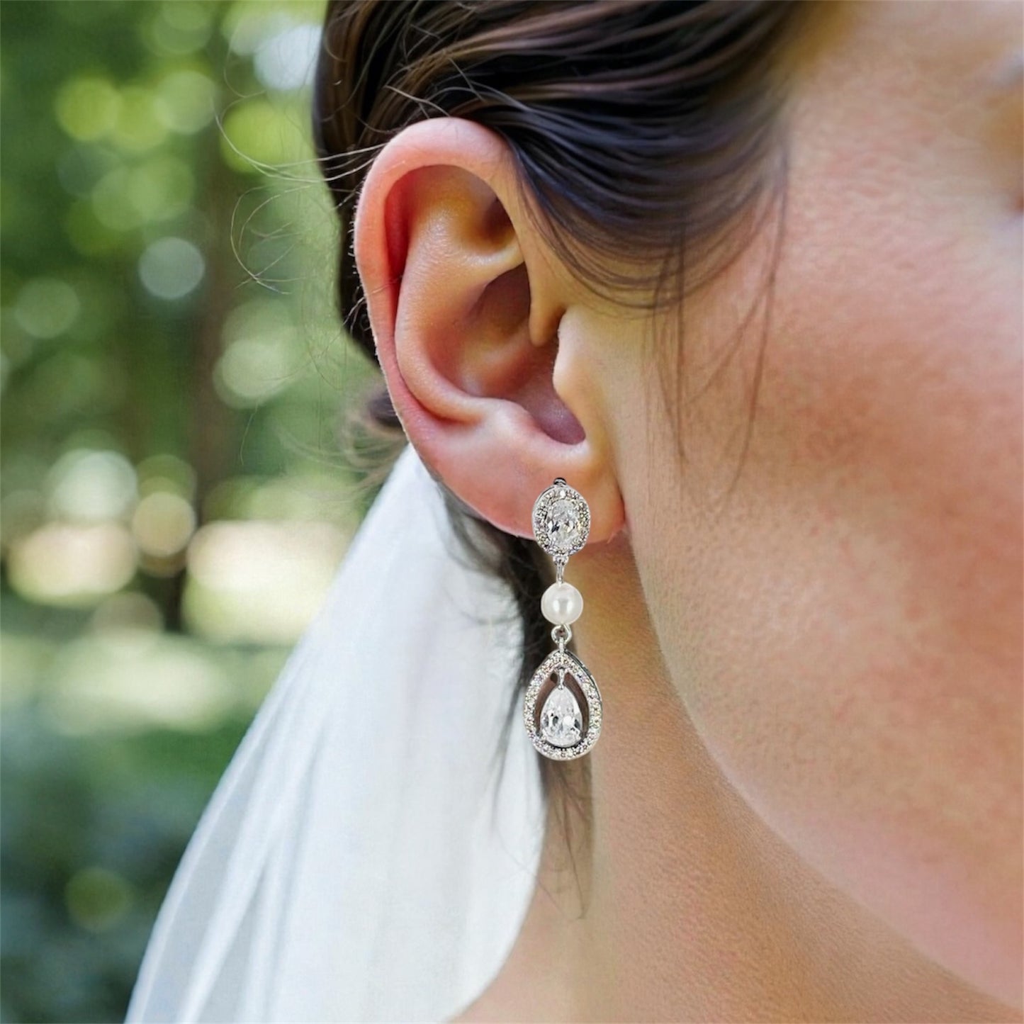 wedding dangle earrings with pearl accent and teardrop crystals on bride's earlobe