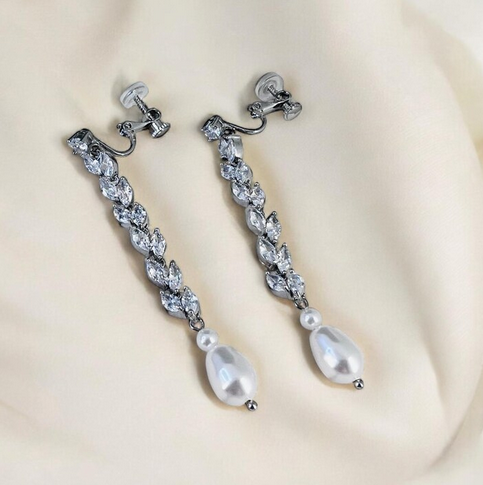 Pair of silver earrings with pearls on a beige background