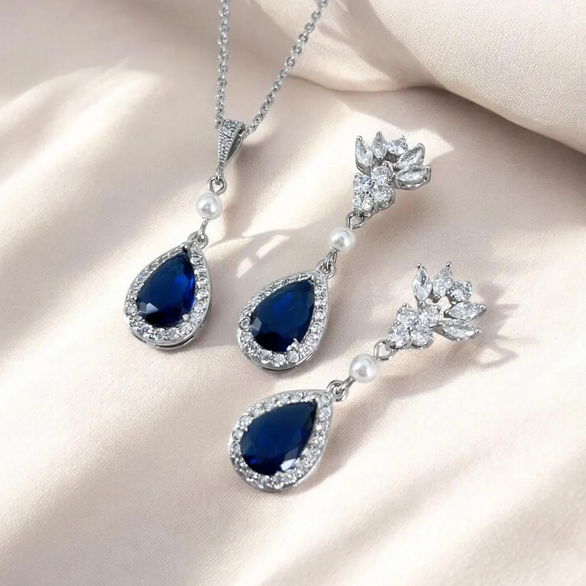 Jewelry set with blue teardrop stones on a beige background