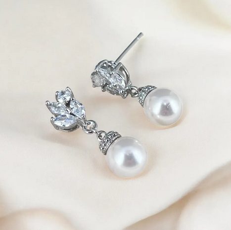 Pearl and crystal earrings on a soft beige background