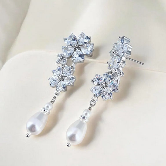 Elegant silver earrings with crystal-like stones and pearl drops on a light background