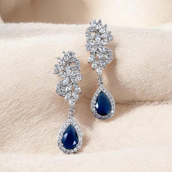 Pair of blue teardrop earrings with silver detailing on a beige surface