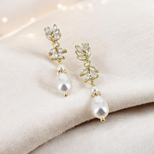 Pearl and CZ floral earrings on a soft fabric background