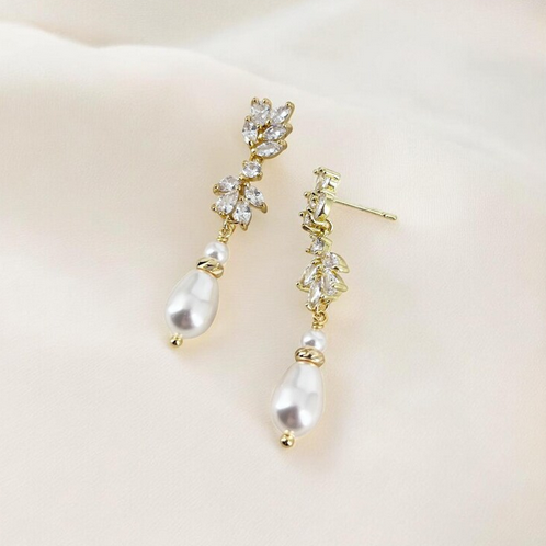 Gold and pearl earrings on a light beige background