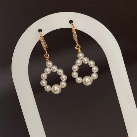 Pearl earrings with gold accents on a white stand 