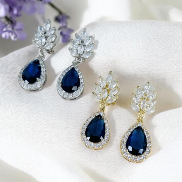 Silver and gold accents sapphire blue teardrop clip on earrings on a white surface