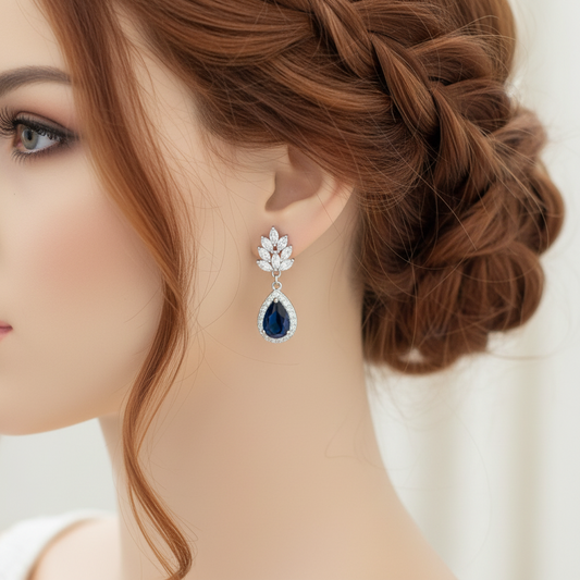 Close-up of a person wearing a sparkling sapphire blue teardrop bridal clip earrings
