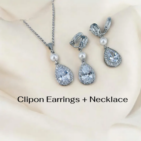 Clipon earrings and necklace set with teardrop-shaped crystals and pearls on a beige background.