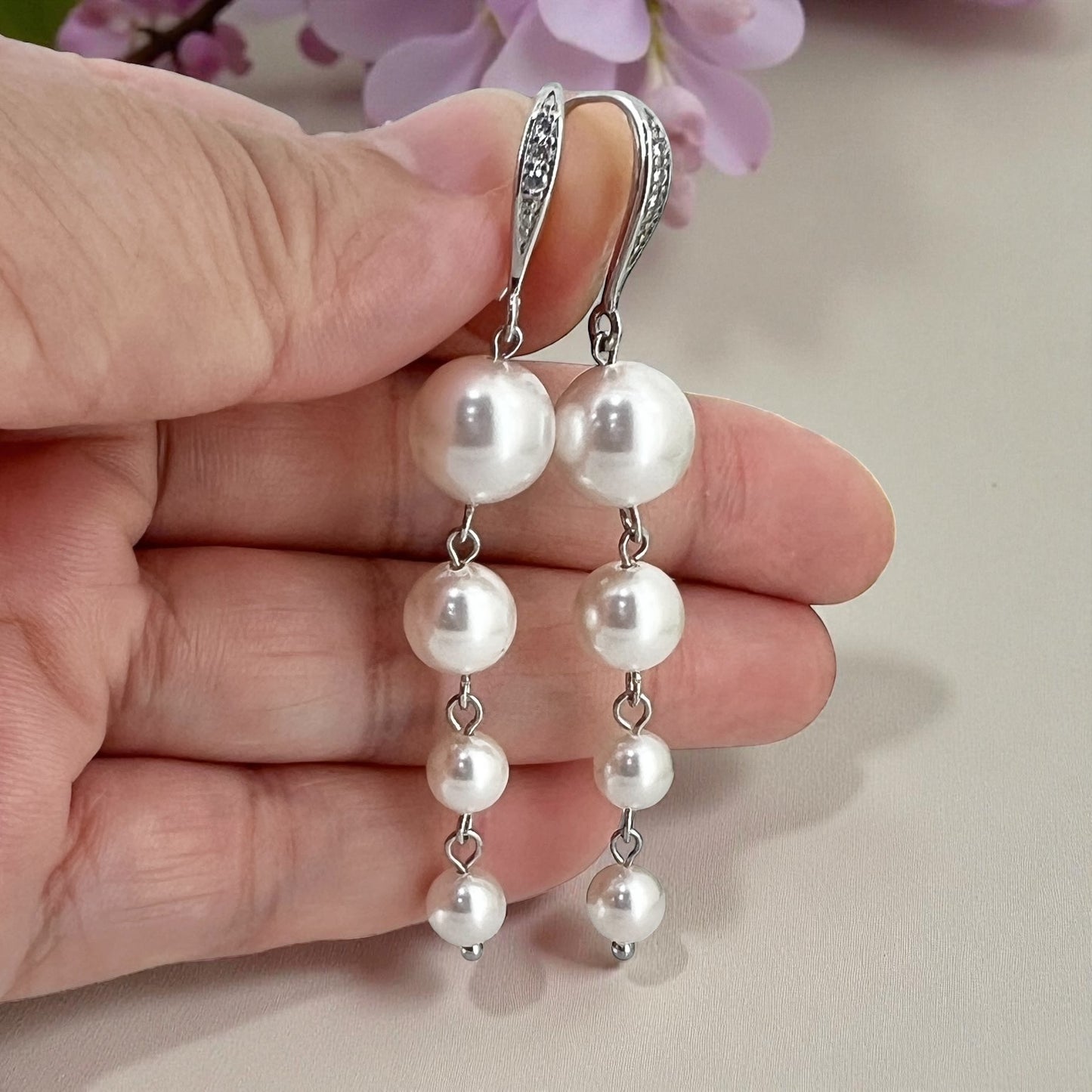 White pearl wedding earrings photographed on hand