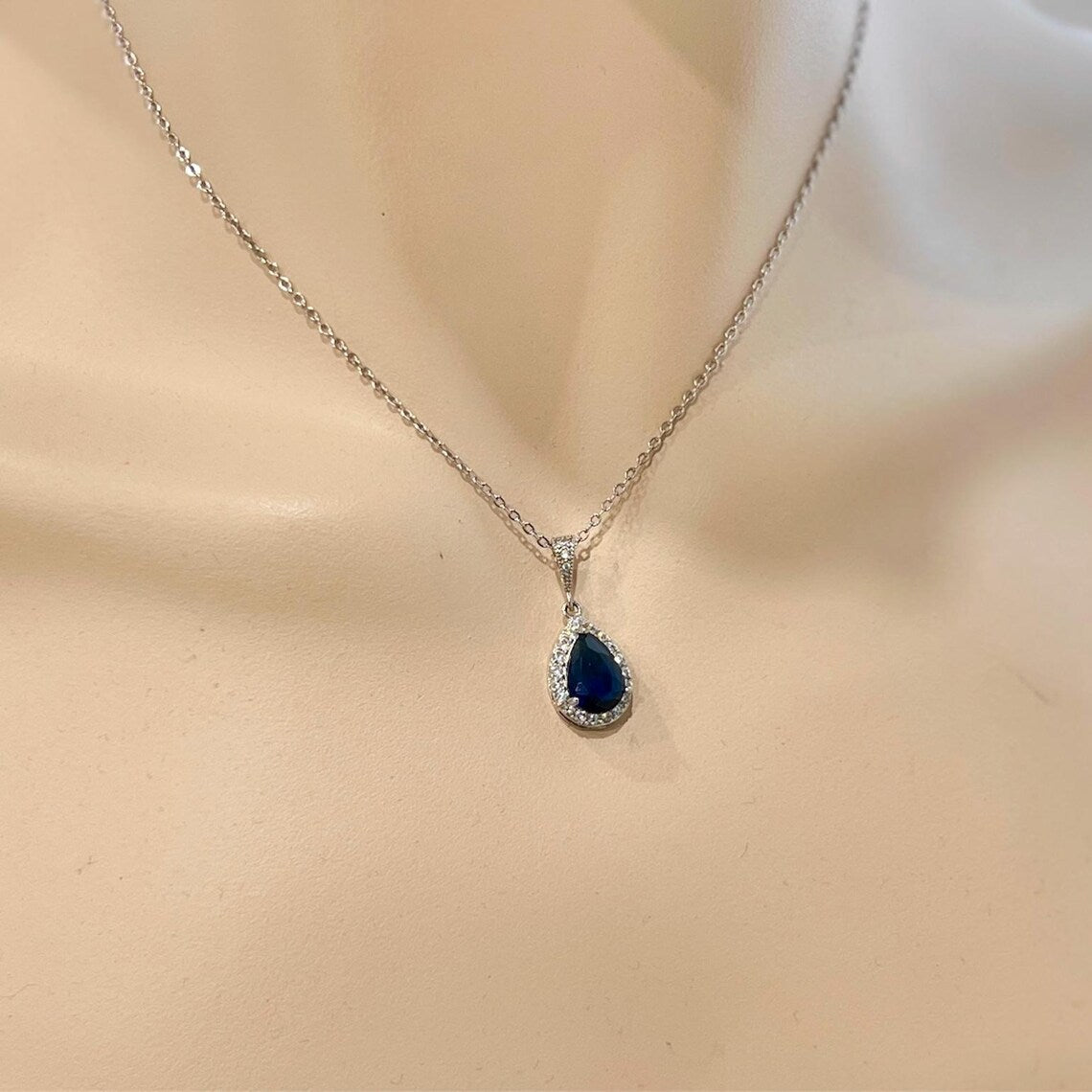 Teardrop-shaped blue gemstone necklace on a mannequin bust.