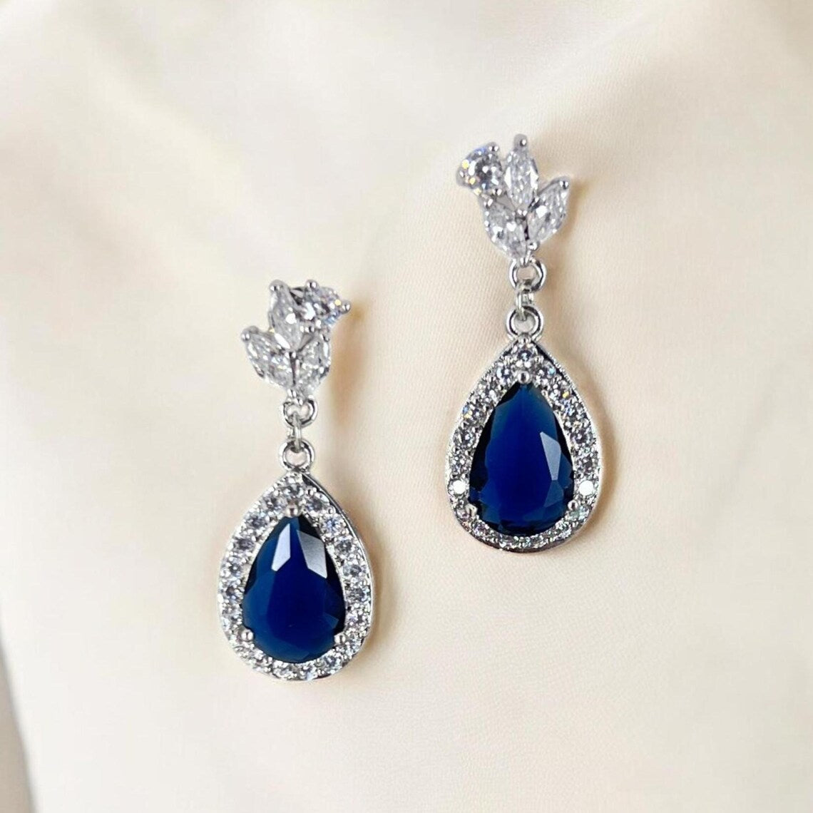 Pair of blue teardrop earrings with silver accents on a light background