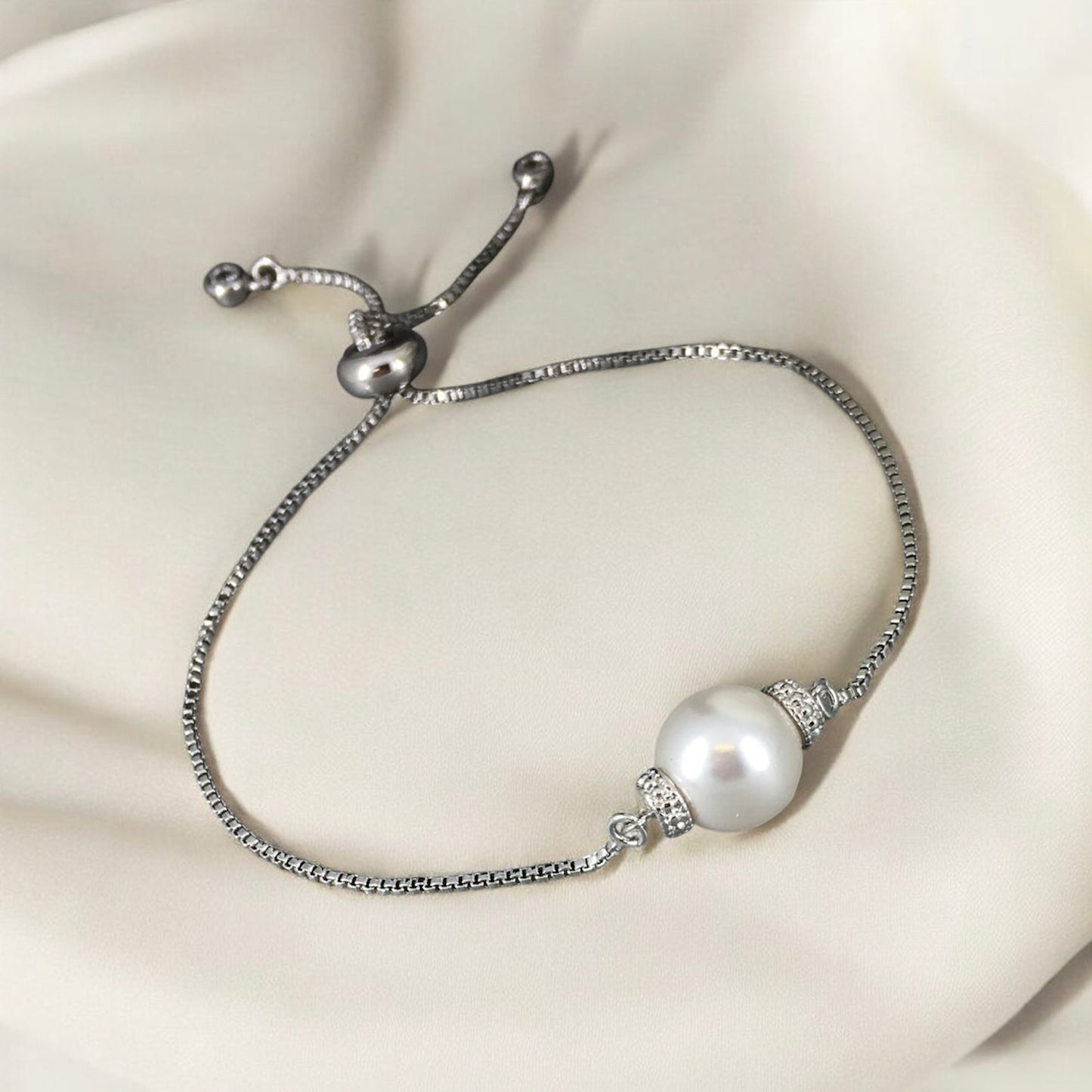 Elegant adjustable white pearl slider bracelet photographed on soft beige background 