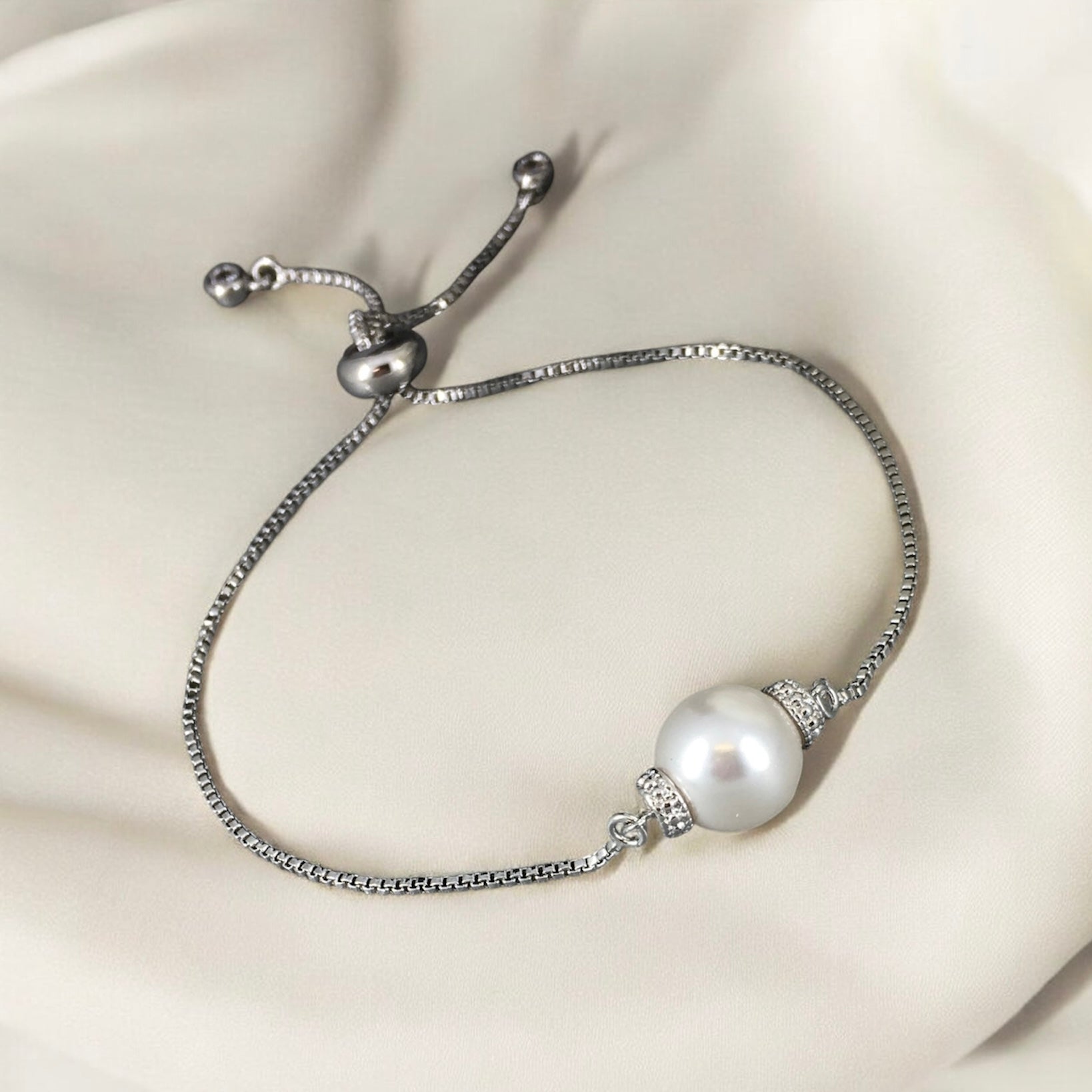 Elegant adjustable white pearl slider bracelet photographed on soft beige background 