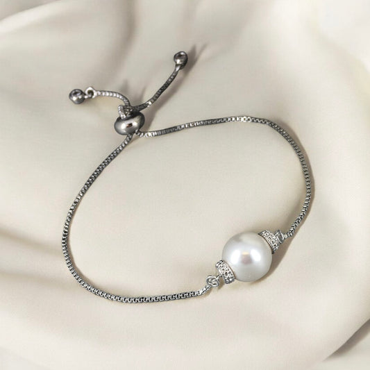 Elegant adjustable white pearl slider bracelet photographed on soft beige background 