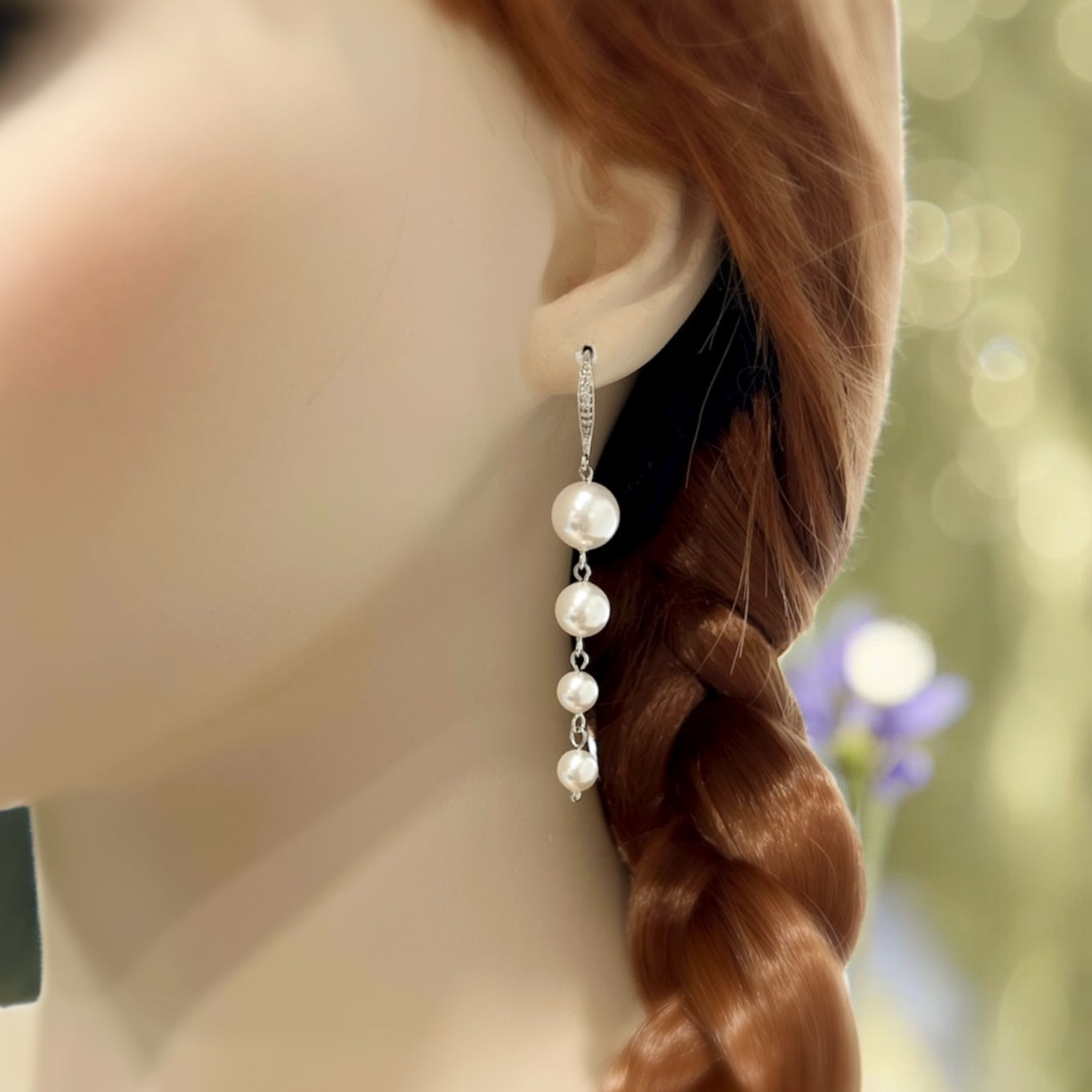 Long white pearl dangle earrings silver bridal jewelry on a model's earlobe